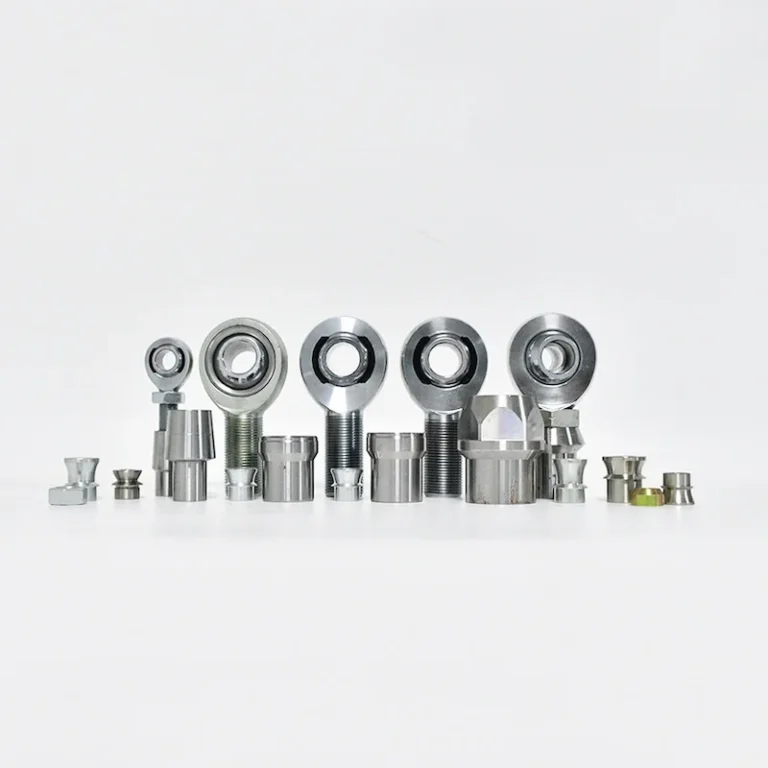 A collection of heim joints with accessories including tube adapters, jam nuts, spacers, and related components, arranged in a row.